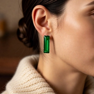 Close-up of elegant emerald green rectangle gemstone earrings worn by a female model