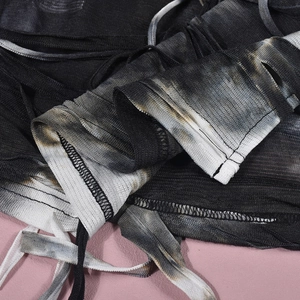 Detail of tie-dye knit crop top featuring distressed holes and drawstring bandage texture
