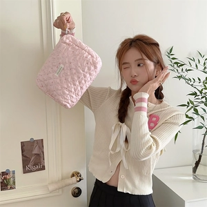 Gros plan détaillé d'une trousse à maquillage rose matelassée tenue par un mannequin