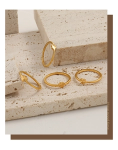 Detailed view of four thin gold rings with heart motifs on travertine stone base