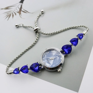 Detail of silver watch band featuring heart-shaped blue stones and adjustable clasp