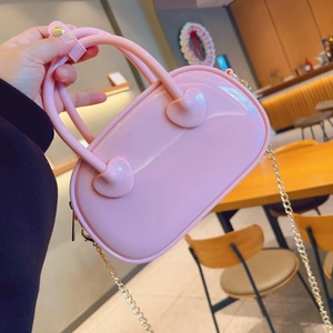 Detail of pink PVC jelly bag with heart-shaped handle connectors and gold metal chain