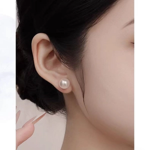 French retro white pearl stud earrings on a female model featuring elegant glossy finish