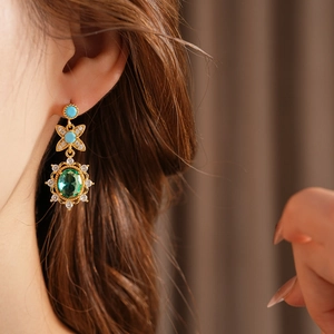 Détail de boucles d'oreilles vintage en or avec gemme ovale verte et cristaux brillants