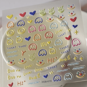3D embossed nail stickers featuring colorful cartoon faces and lucky text patterns