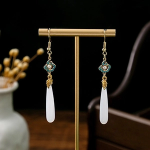Detailed macro view of Chinese style teardrop earrings with golden bamboo and blue enamel flowers