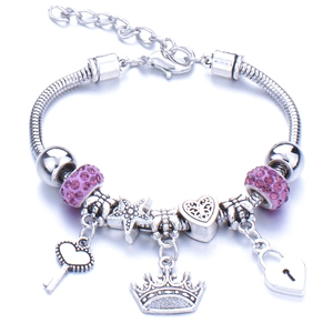 Detail of silver charm bracelet featuring pink crystals, heart key, and crown pendants