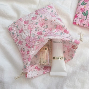 Detailed shot of pink floral drawstring storage bag with seersucker texture and skincare inside