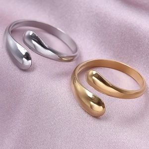 Macro shot of silver and gold teardrop open rings on elegant pink silk fabric background