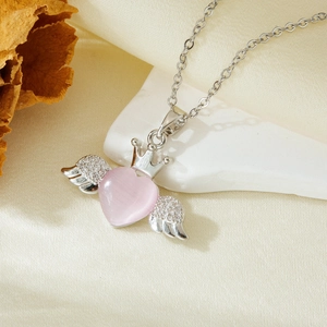 Silver necklace detail with pink heart crown pendant and diamond-set angel wings charm