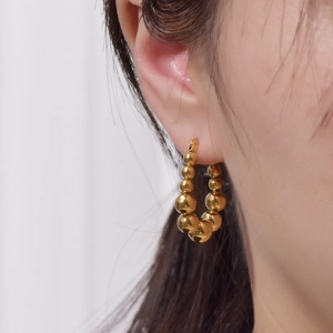 Detail von 18K Gold Schlangenschuppen Edelstahl Creolen an einem Model gezeigt