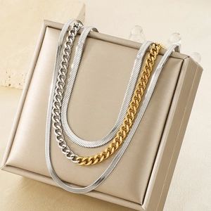 Detail of layered gold and silver Cuban and snake chains on a beige display stand