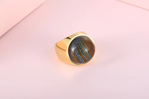 Macro detail of wide gold stainless steel ring with cosmic colorful foil glass inlay