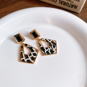 Gros plan de boucles d'oreilles dorées avec motif zébré noir et blanc en acétate