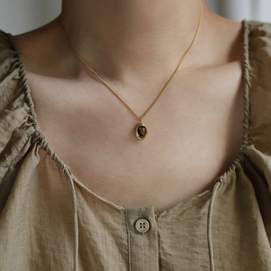 Close-up of vintage golden titanium steel necklace with brown tiger eye stone pendant
