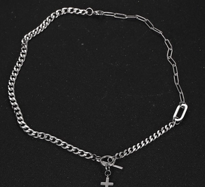 Close-up of silver cross necklace featuring Cuban and paperclip chain with OT clasp