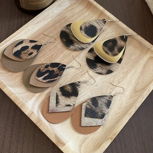 Detail of layered leather teardrop earrings with leopard print and golden metallic textures