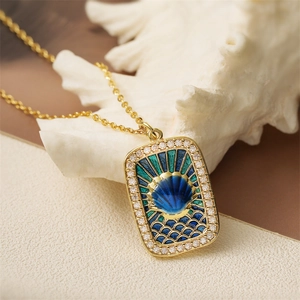 Gold tarot style pendant necklace with blue enamel shell and crystals on white coral