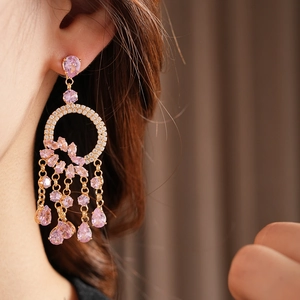 Detail of pink crystal tassel earrings with sparkling teardrop gemstones in gold finish