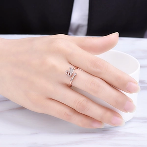Rose gold swan open ring with sparkling diamonds worn on finger against white marble