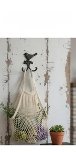 Close-up of vintage black cast iron wall hook with bird design on a rustic wood board