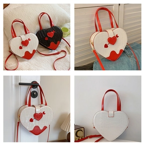 Detail of heart-shaped crossbody bags with crocodile texture in white and black