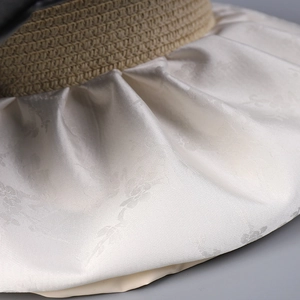 Détail du tissu satiné jacquard floral et de la texture paille tressée du bord d'un chapeau