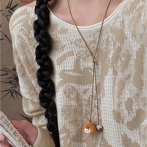 Ethnic wax cord necklace with nut-shell doll pendant on a model with bamboo backdrop