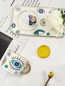 Detailed view of evil eye ceramic mug set with golden handle on elegant table setting