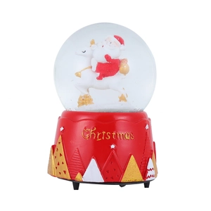 Close-up of a Christmas snow globe with Santa on a reindeer and a red festive base