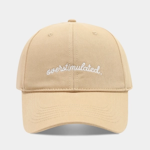 Minimalist beige baseball cap featuring white 'overstimulated.' script embroidery
