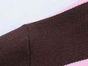 Dettaglio della cucitura della spalla su maglia marrone con bordi a righe rosa e nere