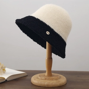 Détail chapeau bob en tricot avec bord en fausse fourrure noire et logo JS doré