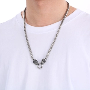 Detail of silver double lion head pendant with round ring on steel Cuban link chain