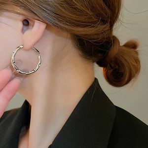 Close-up of irregular textured silver hoop earrings worn by a model in a profile view