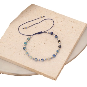 Adjustable woven bracelet with blue natural stone beads and gold metal spacers on stone base