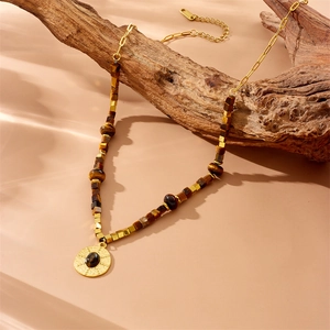 Vintage style beaded necklace with gold metal chain and brown stones on wood