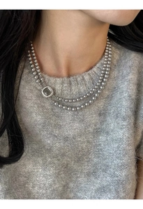 Detail of grey pearl double necklace with a square diamond-studded shell pendant