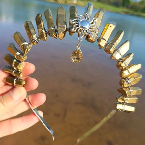 Detail of gold crystal tiara featuring sun pendant and wire-wrapped quartz stones