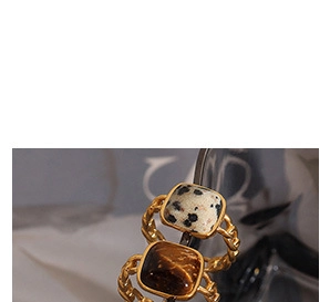 Close-up of golden chain rings with square tiger eye and marble stone inlays