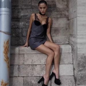 Elegante abito grigio a sottoveste con pizzo nero indossato da una modella su scale