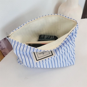 Blue striped canvas toiletry bag detail with Pleasant Times label and metal zipper