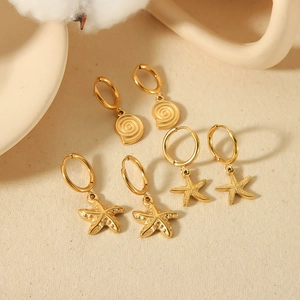 Three pairs of 18K gold plated starfish and shell earrings on a warm beige background