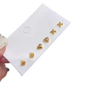 Three-pair gold geometric stud earring set including heart, cross, and square shapes