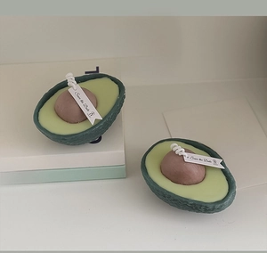 Artistic detail of avocado-shaped handmade soy wax scented candles in a home setting