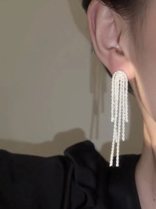 Close-up of sparkling silver tassel earrings worn, featuring shimmering fringe detail