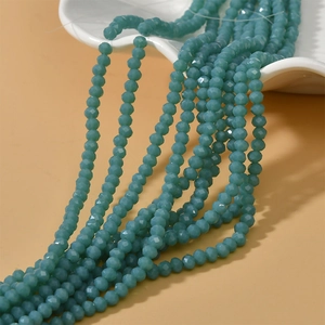 Detail of 4mm blue faceted rondelle crystal beads cascading from a ceramic dish for DIY jewelry