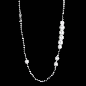 Detail of gradient pearls and silver bead chain with bow clasp on black background