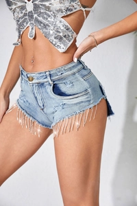 Gros plan sur les franges en strass scintillants et les détails déchirés du short en jean