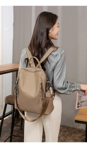 Detailed view of khaki PU leather backpack with adjustable straps in a modern cafe setting